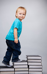 Image showing Young man climbing on a ladder of books