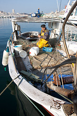 Image showing MARSEILLE, FRANCE,  MARCH 6: a fisherman, on the knees in his boat, in the Vieux-Port, tidies up his nets, on Sunday, March 6th, 2011 in Marseille, France.