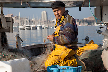 Image showing MARSEILLE, FRANCE,  MARCH 6: a fisherman, on the knees in his boat, in the Vieux-Port, tidies up his nets, on Sunday, March 6th, 2011 in Marseille, France.