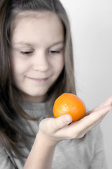 Image showing The girl and a tangerine