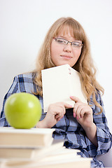 Image showing The girl with the book looks at an apple