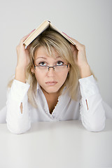 Image showing The young woman hides under the book