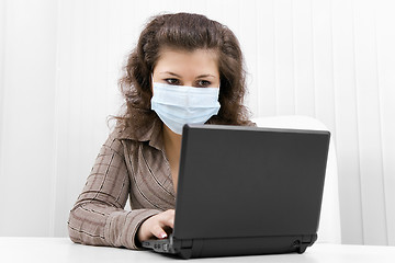 Image showing The young woman in medical mask with the laptop