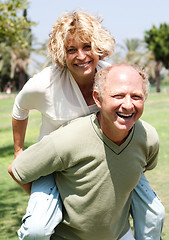 Image showing Senior man giving piggy ride to her wife