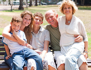 Image showing happy family sitting on park bench