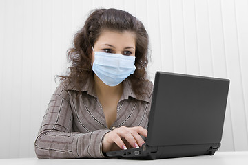 Image showing The young woman in medical mask with the laptop