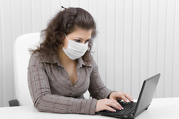 Image showing The young woman in medical mask with the laptop