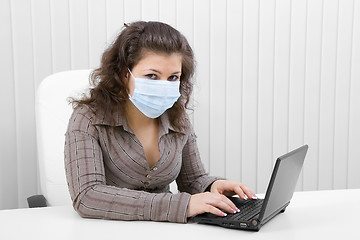 Image showing The young woman in medical mask with the laptop