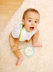 Image showing Baby boy sitting on carpet and eating alone