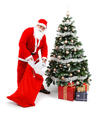 Image showing Santa Claus putting gifts under christmas tree