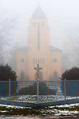 Image showing Church in the fog with stone cross and fence