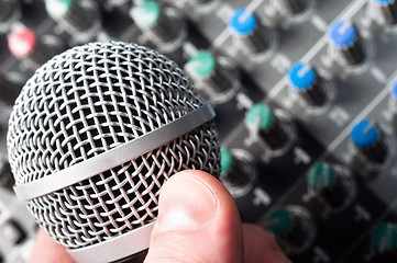 Image showing Part of an audio sound mixer with microphone in hand