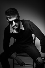 Image showing Young man sitting in chair  in sunglasses in shirt in black and 