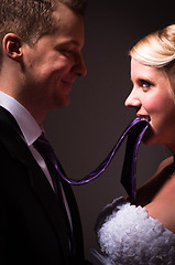 Image showing Beautiful young bride holding her groom on a leash