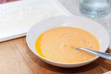 Image showing Egg in plate on wooden board with flour in background