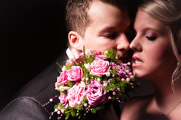 Image showing young couple in wedding wear with bouquet of roses