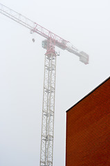 Image showing Red bwall made out of brick with construction crane in backgroun