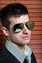 Image showing Close-up of a young man in sunglasses against blinds