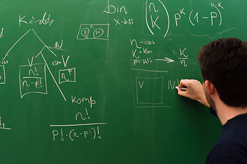 Image showing Young student writing formulas on green chalk board