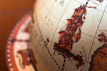 Image showing Part of a globe with old ship on blurry background