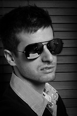 Image showing Close-up of a young man in sunglasses against blinds in black an