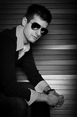 Image showing Young man sitting in the window with sunglasses in black and whi