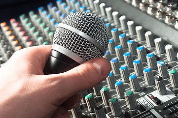 Image showing Part of an audio sound mixer with microphone in hand