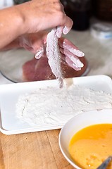 Image showing Fresh meat with flour on in the hands of a cook with blurry back