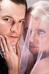 Image showing Young bride in veil holding the chin of the groom