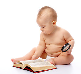 Image showing Little child play with book and magnifier