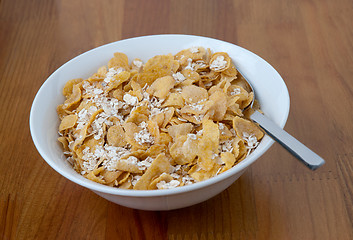 Image showing White bowl with a spoon, corn and oats flakes
