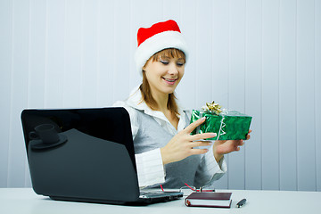 Image showing Working Girl in Santa hat with a gift