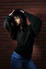 Image showing fashion portrait of young woman with a brick wall