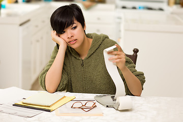 Image showing Multi-ethnic Young Woman Agonizing Over Financial Calculations