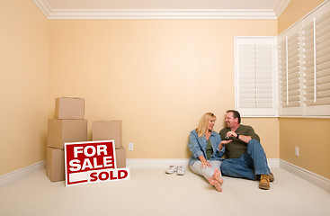 Image showing Couple on Floor Near Boxes and Sold Real Estate Signs