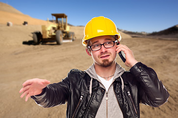 Image showing Young Cunstruction Worker on Cell Phone in Dirt Field with Tract
