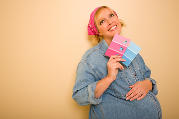 Image showing Pensive Pregnant Woman Holding Pink and Blue Paint Swatches
