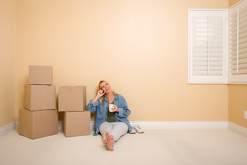Image showing Happy Woman Relaxing Next to Boxes on Floor with Cup