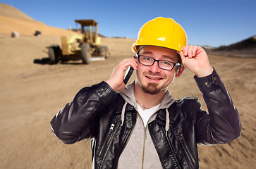 Image showing Young Cunstruction Worker on Cell Phone in Dirt Field with Tract