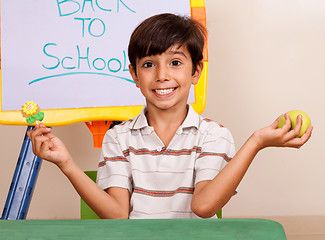 Image showing Cheerful school boy holding an apple