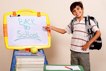 Image showing Smiling school boy pointing at white board