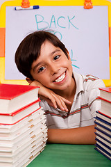 Image showing Young boy with stack of books