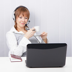 Image showing girl-employee hotline is drinking coffee