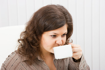 Image showing Brunette girl is drinking coffee from a cup