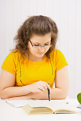 Image showing A young woman in spectacles is reading a book