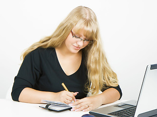 Image showing girl with a laptop writes in a notebook