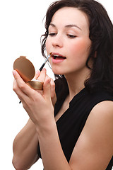 Image showing Woman is applying lipgloss while looking in mirror