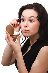 Image showing Woman is applying mascara while looking in mirror