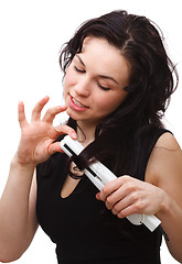Image showing Woman is using hair straightener