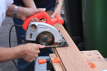 Image showing construction worker cutting wood with circular saw